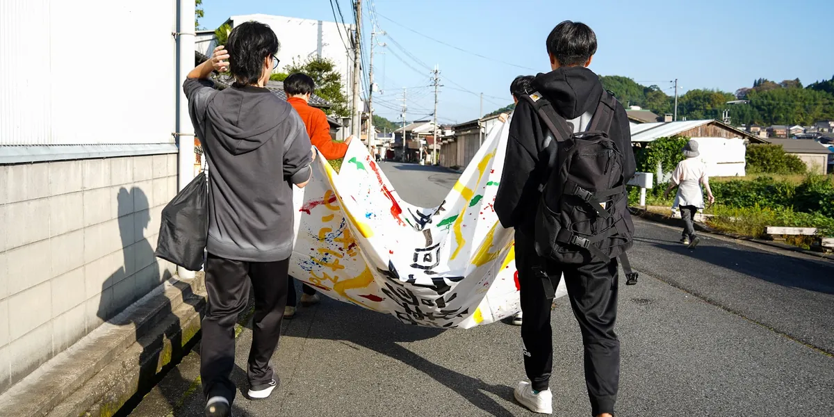 横断幕を持って、町の道を歩く