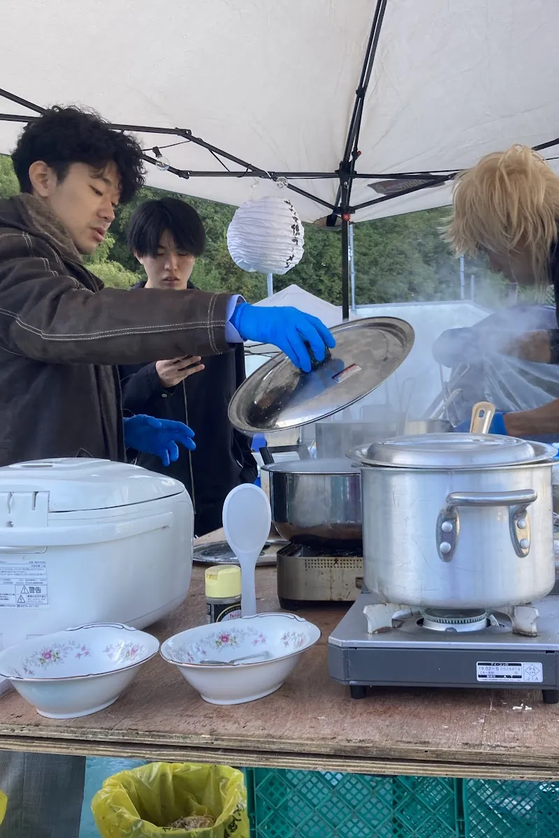 テントで大鍋と炊飯器を使って調理するスタッフ